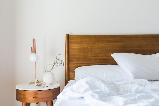 bed-with-a-wooden-frame-white-sheets-and-a-wooden-side-table